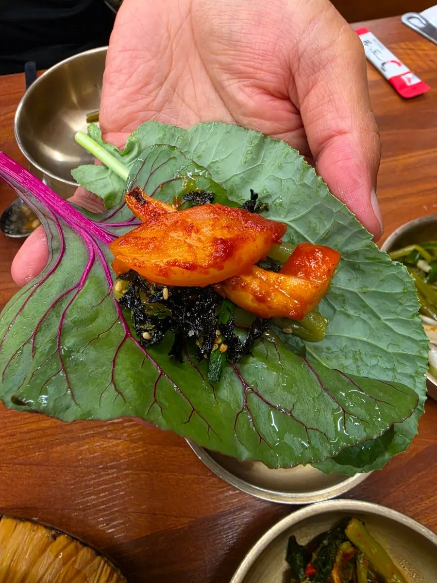 A meal with seasoned greens and wraps