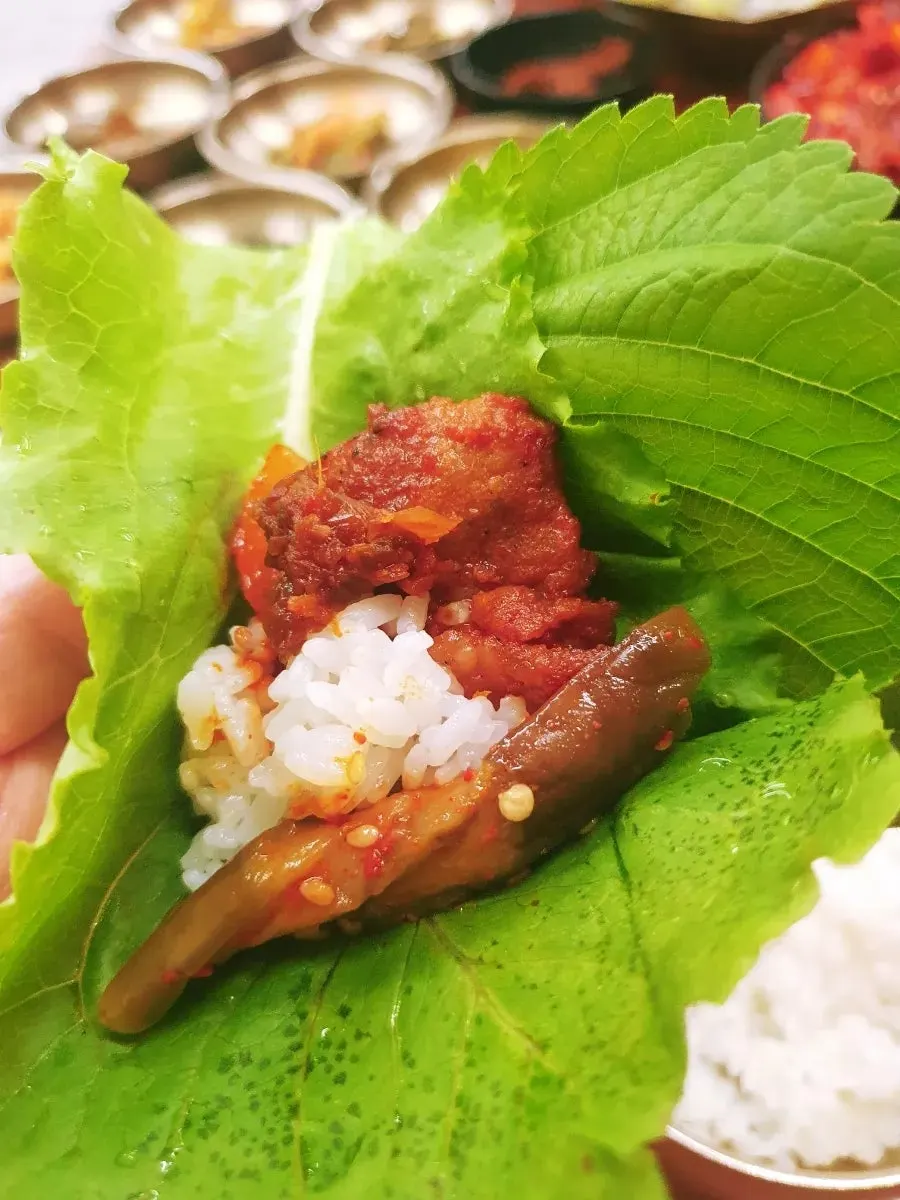 Hoja de ssam con arroz y banchan encima