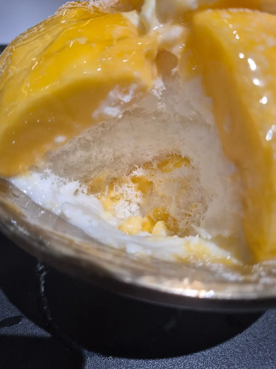 A spoonful of bingsu eaten with purée drizzled on