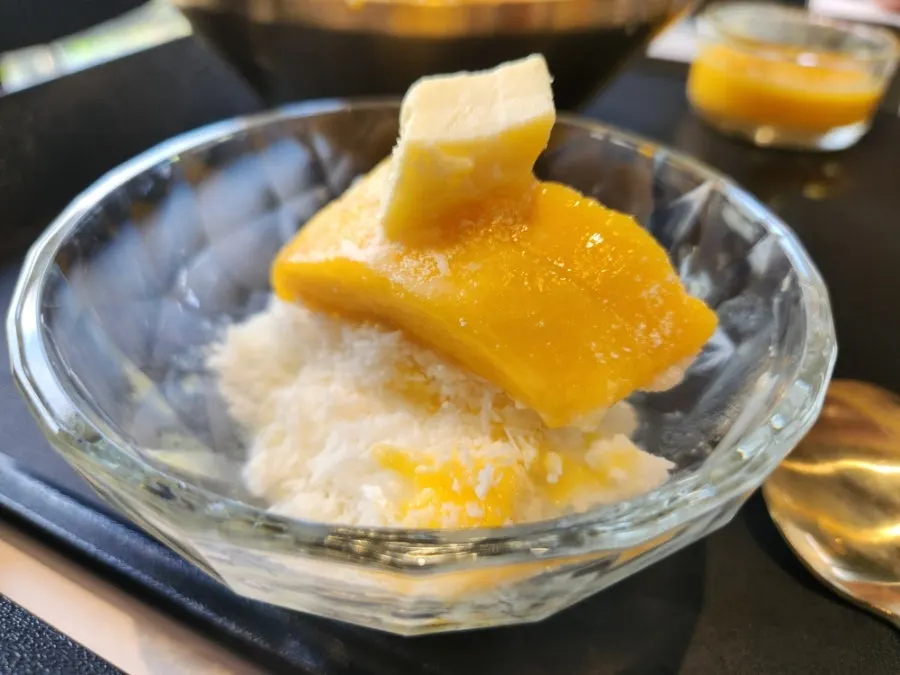 Scooping a spoonful of fresh mango snow bingsu