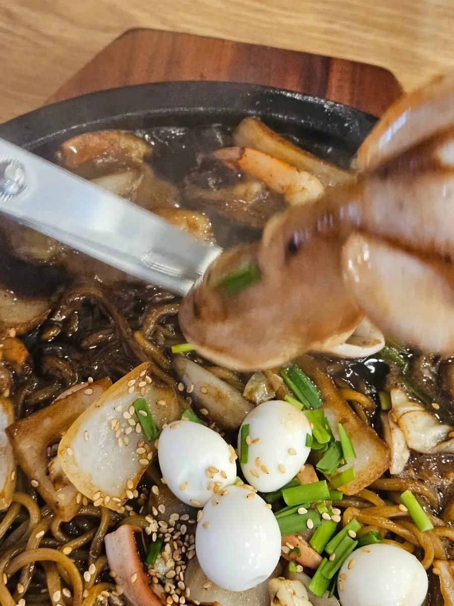 Stone-plate jajangmyeon topped with seafood and a whole squid