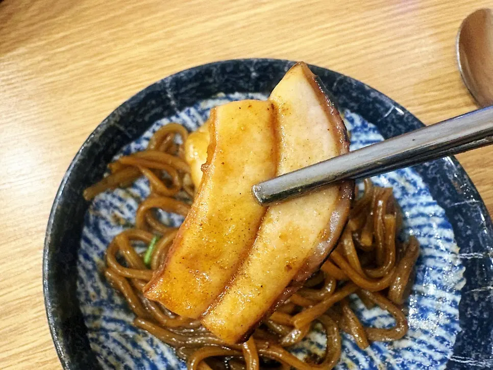 Stone-plate jajajang noodles scooped onto a small plate and mixed