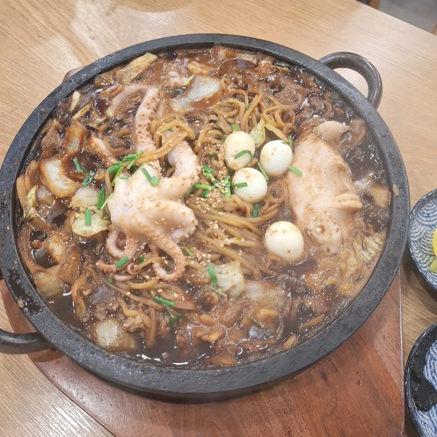 Noodles with squid and octopus sizzling on the stone plate