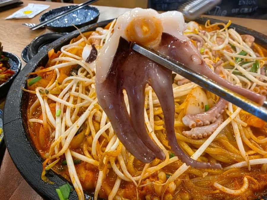 Whole octopus lifted up with tongs