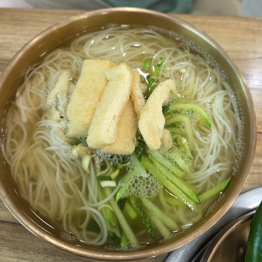 Clear janchi guksu topped with zucchini and fried tofu skin