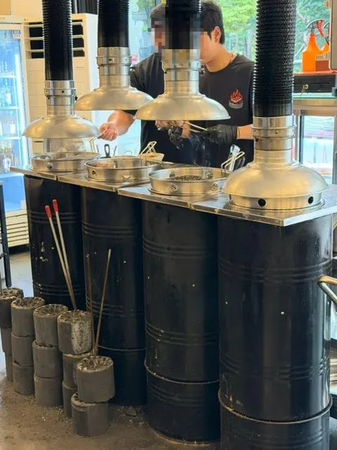 Charcoal pre-grill station in a drum barrel by the entrance