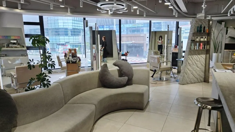 Interior of Tthe Art Hair Unjeong Station Branch with floor-to-ceiling windows