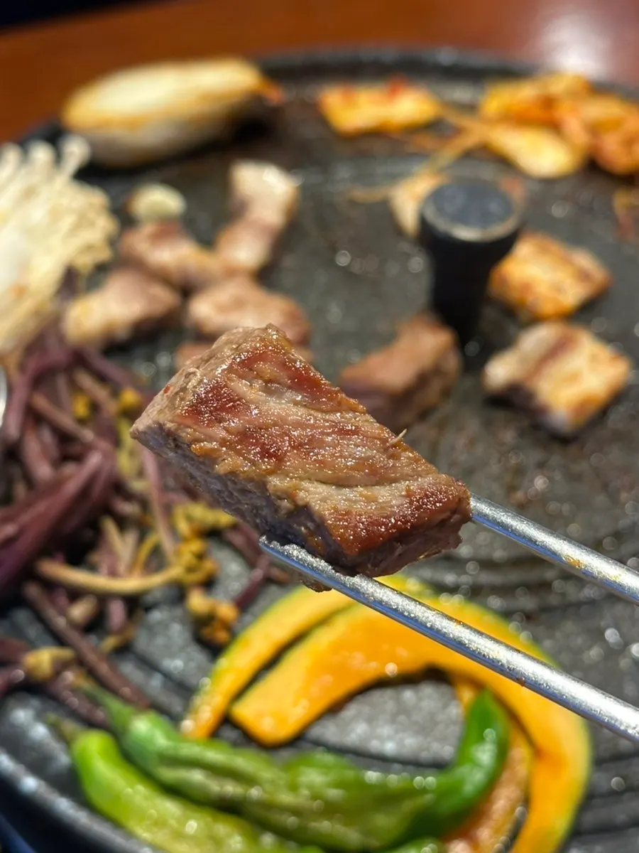 A piece of pork belly grilled on a pot lid
