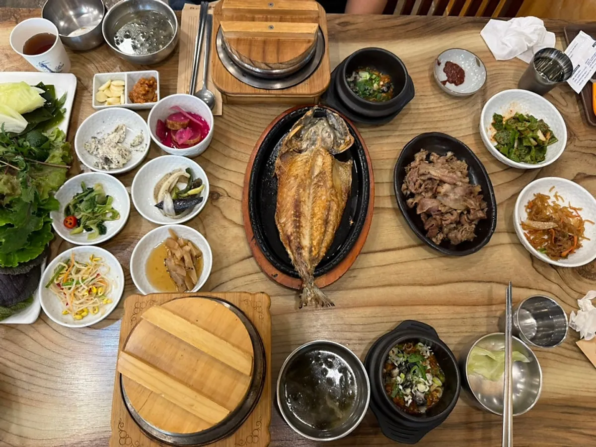 Table spread of bulgogi, mackerel, hot-stone rice, and ureong ssamjang