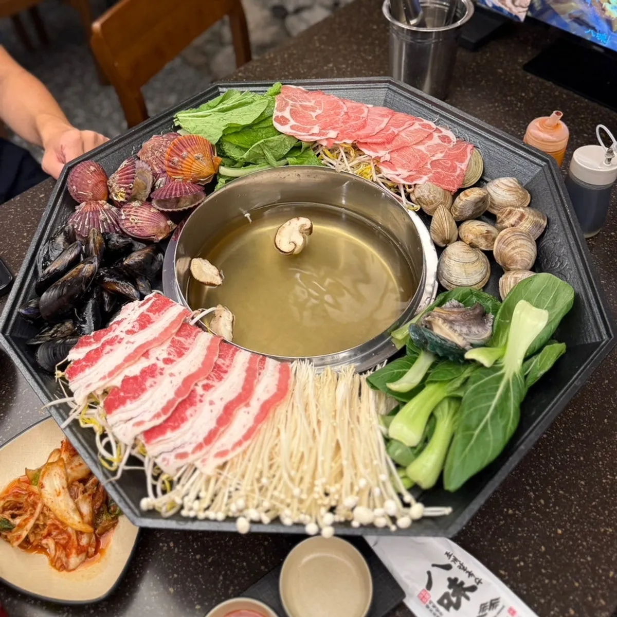A large pot of clams, vegetables, and beef