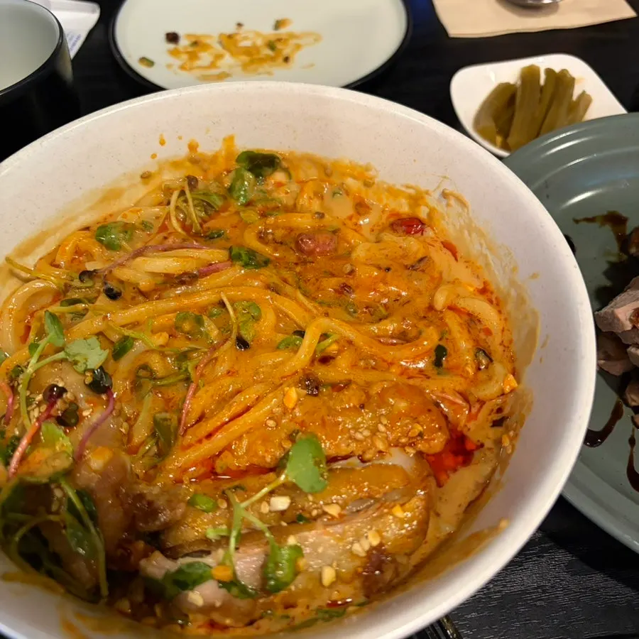 Large chunk of chicken on top of the dan dan noodles