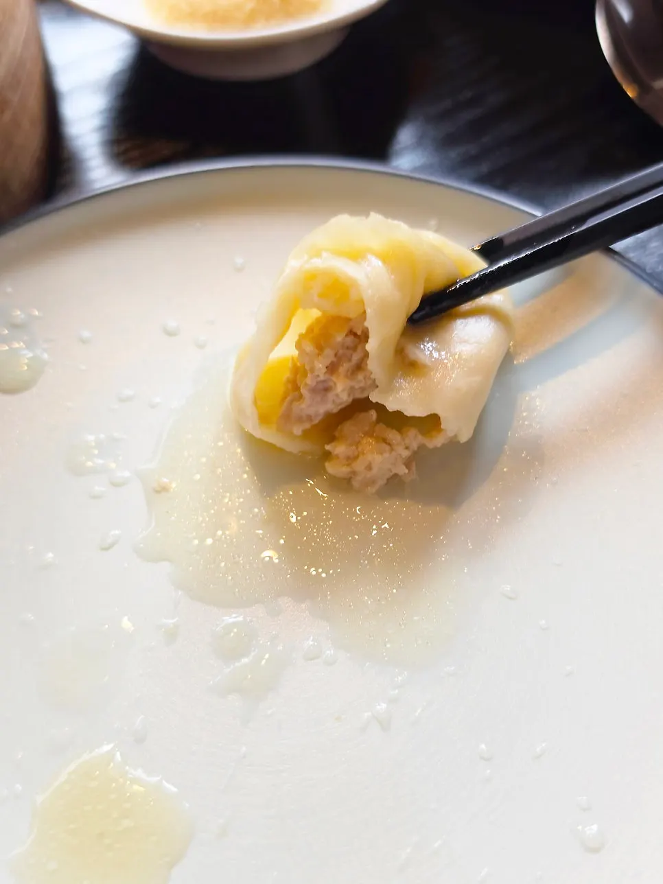 Broth spilling from a cut-open xiaolongbao