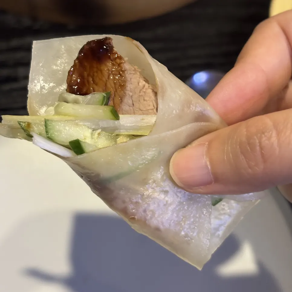 Wrapping cucumber, scallion and Peking duck in a pancake