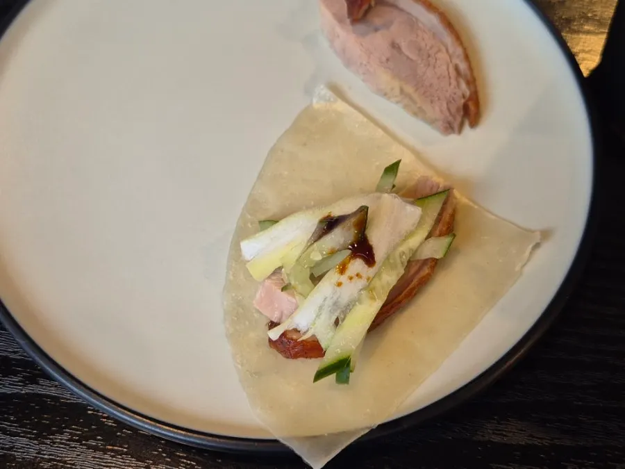 Wheat pancake topped with duck meat, cucumber, and scallion