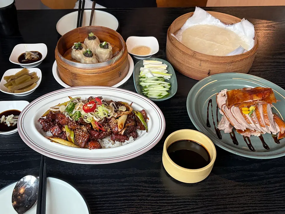 Table spread with Peking duck, dim sum, and the rice bowl together