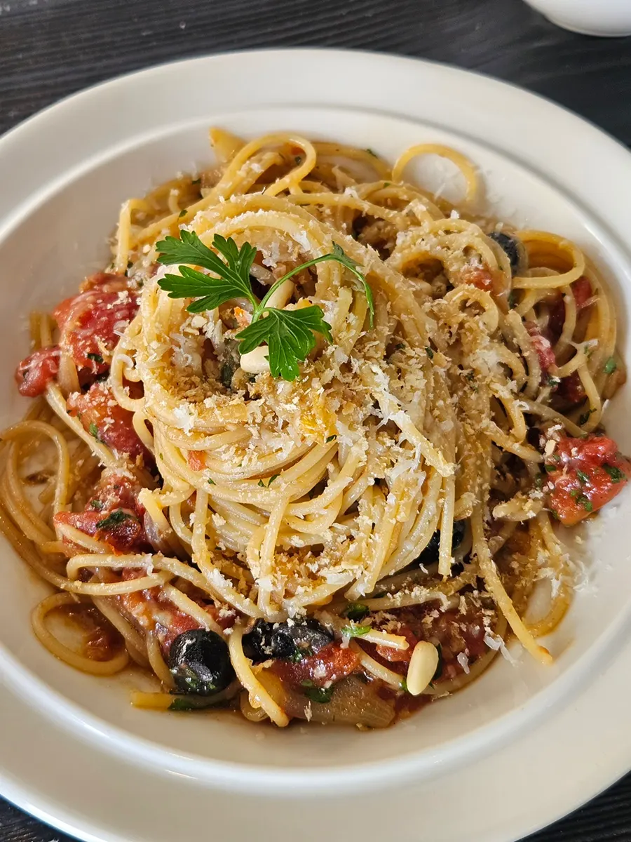 Anchovy pasta topped with tomato and olives