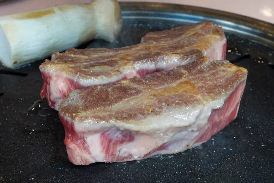 Thick Iberico pork neck grilling on the grill plate