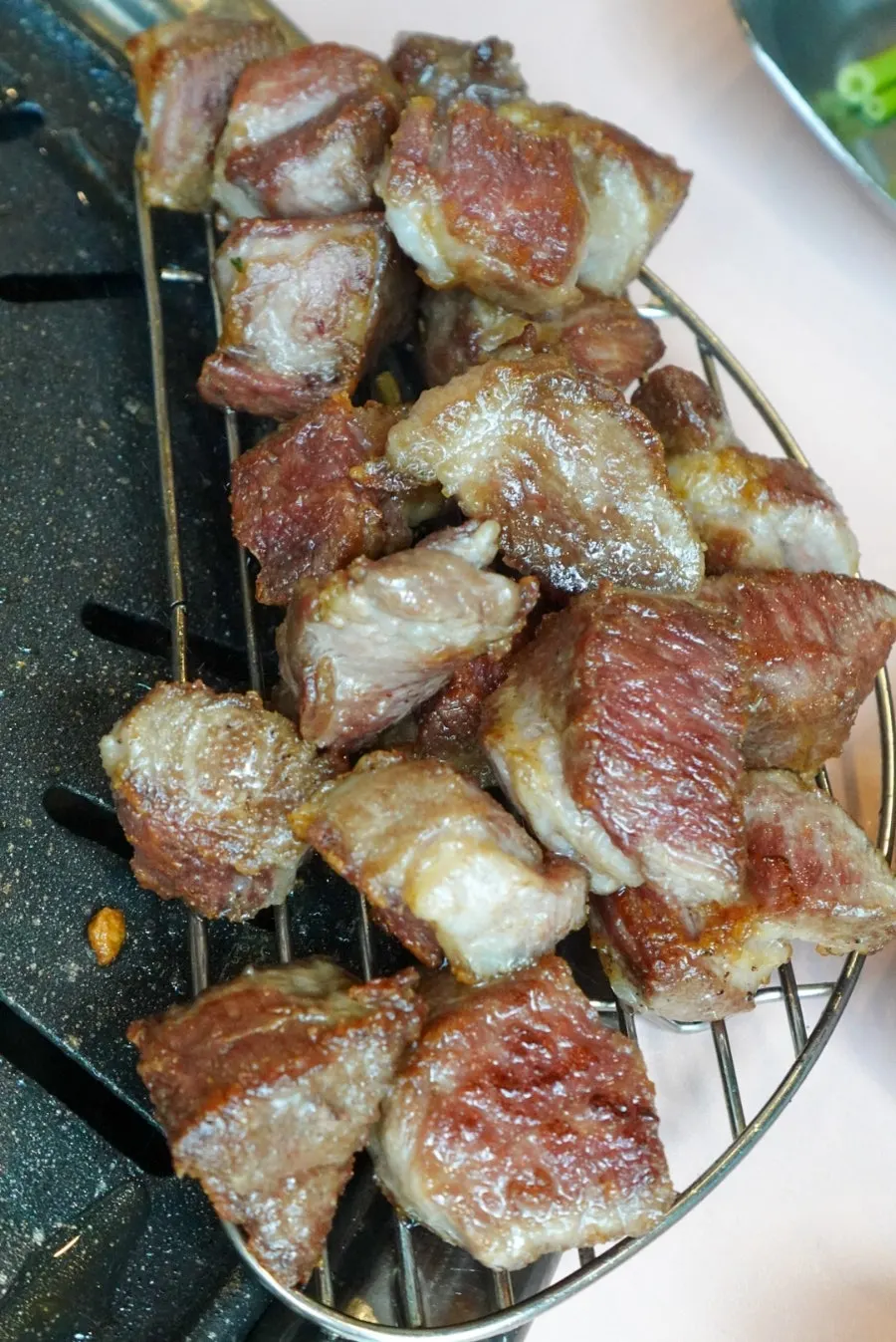 Iberico pork neck pieces being grilled a second time