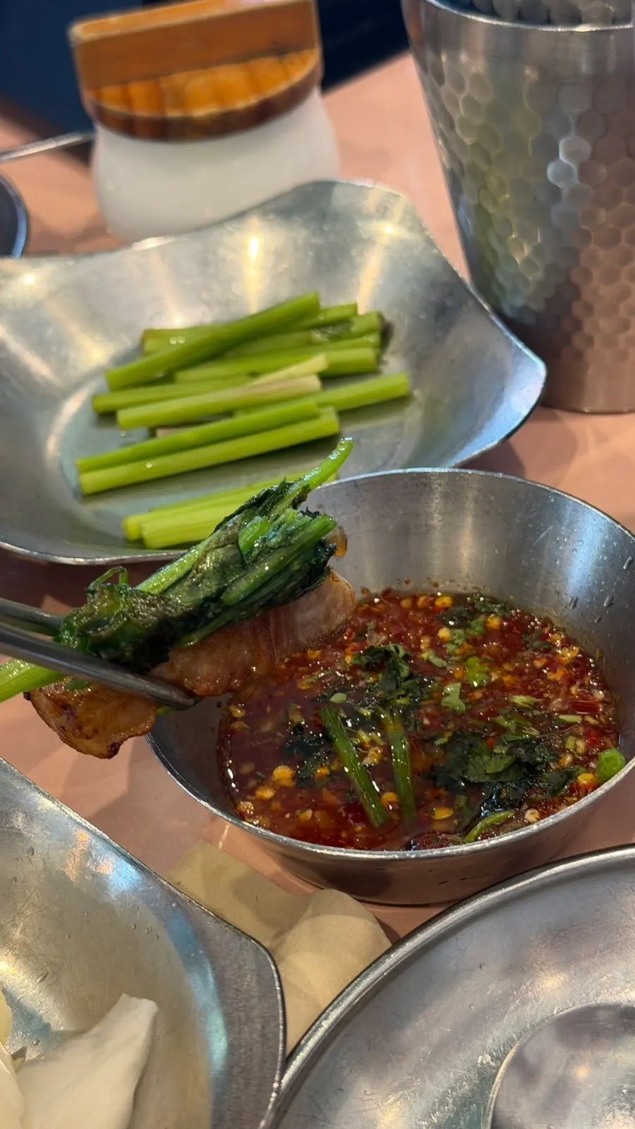 A piece of pork belly topped with minari and fish sauce