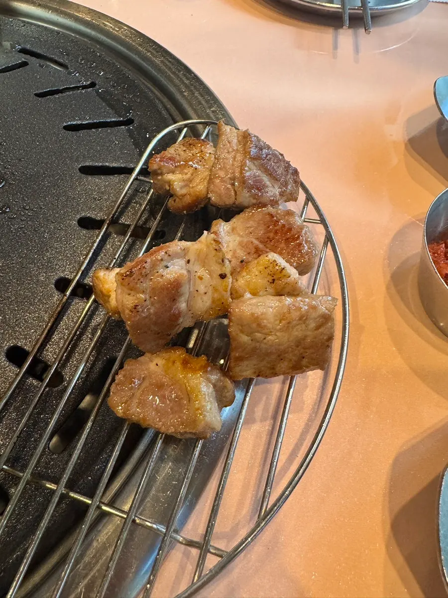 Grilled pork belly being plated piece by piece