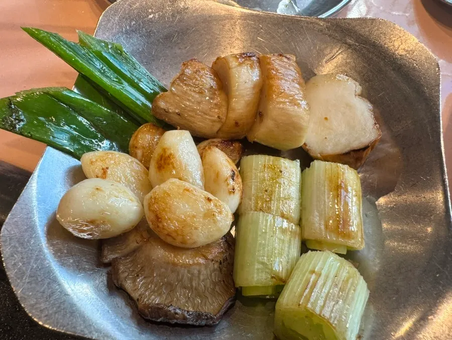 A plate of meat served together with grilled vegetables