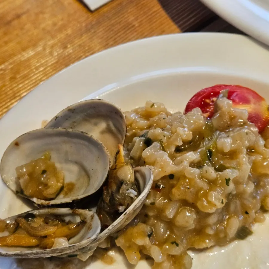 Spoonful of clam risotto with a clam on top