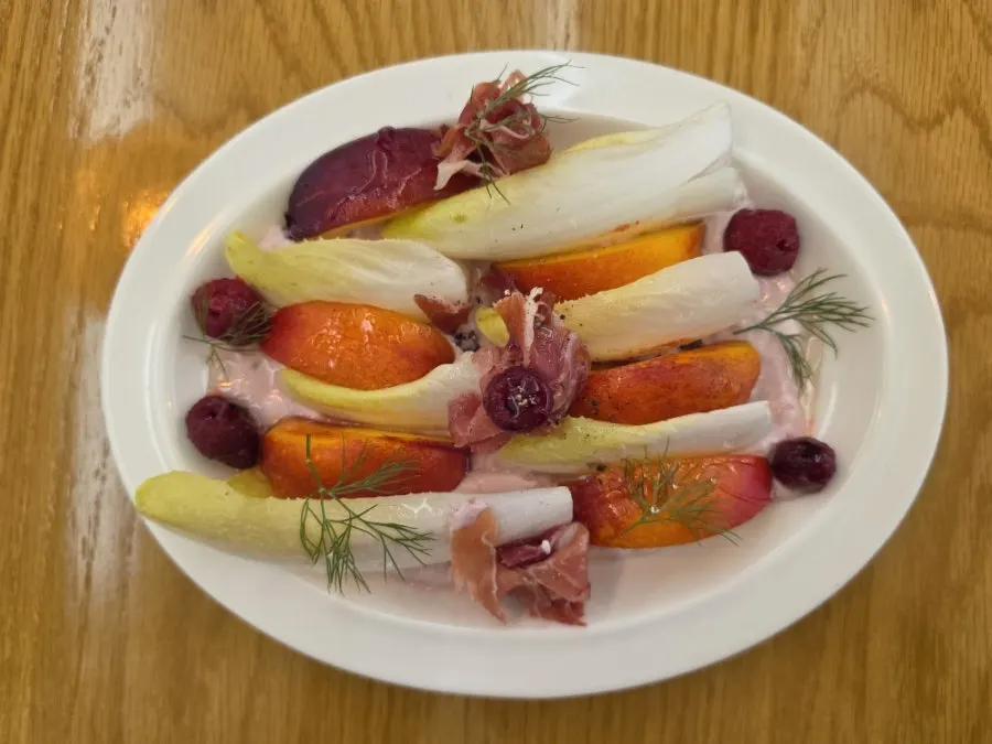 Close-up of the salad topped with peach and jamón
