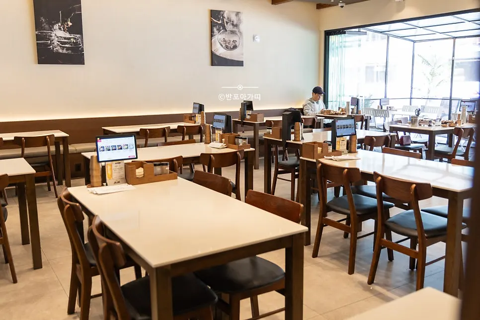 Main hall of Useum Pangyo Branch with wood-toned tables