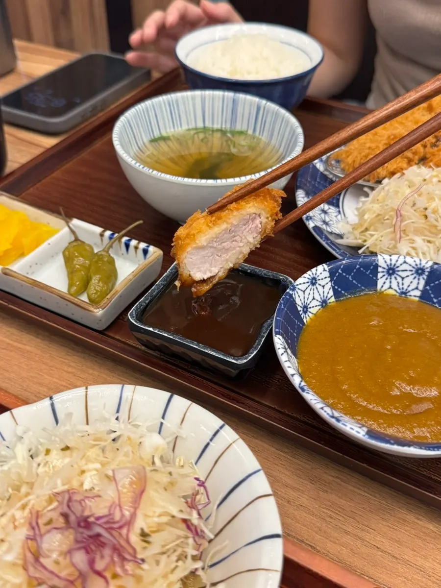 A piece of hire katsu dipped in tonkatsu sauce