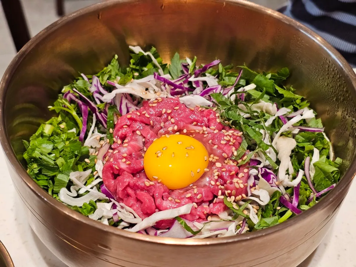 Yukhoe bibimbap topped with egg yolk and Korean beef