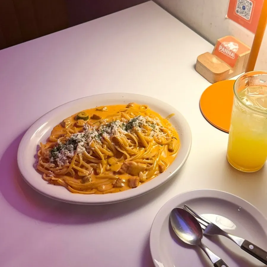 Table setting with the ordered fire noodle carbonara and orange-ade