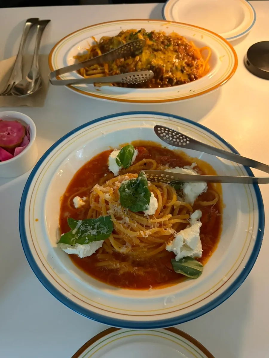 個人用トングと取り皿が一緒に出されたパスタの食卓