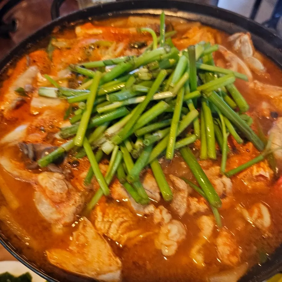 Pot of Yeonpyeong Island crab roe alkoni-tang topped with minari