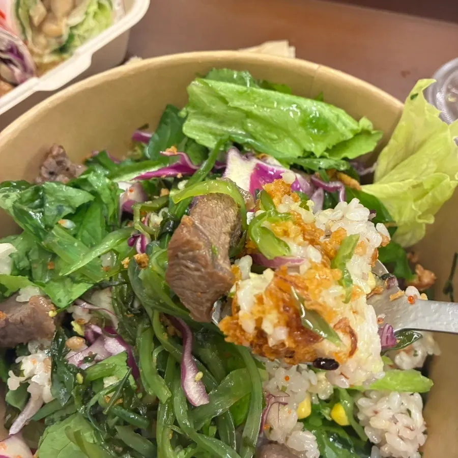 Close-up of skirt steak poke with vegetables, rice, and toppings