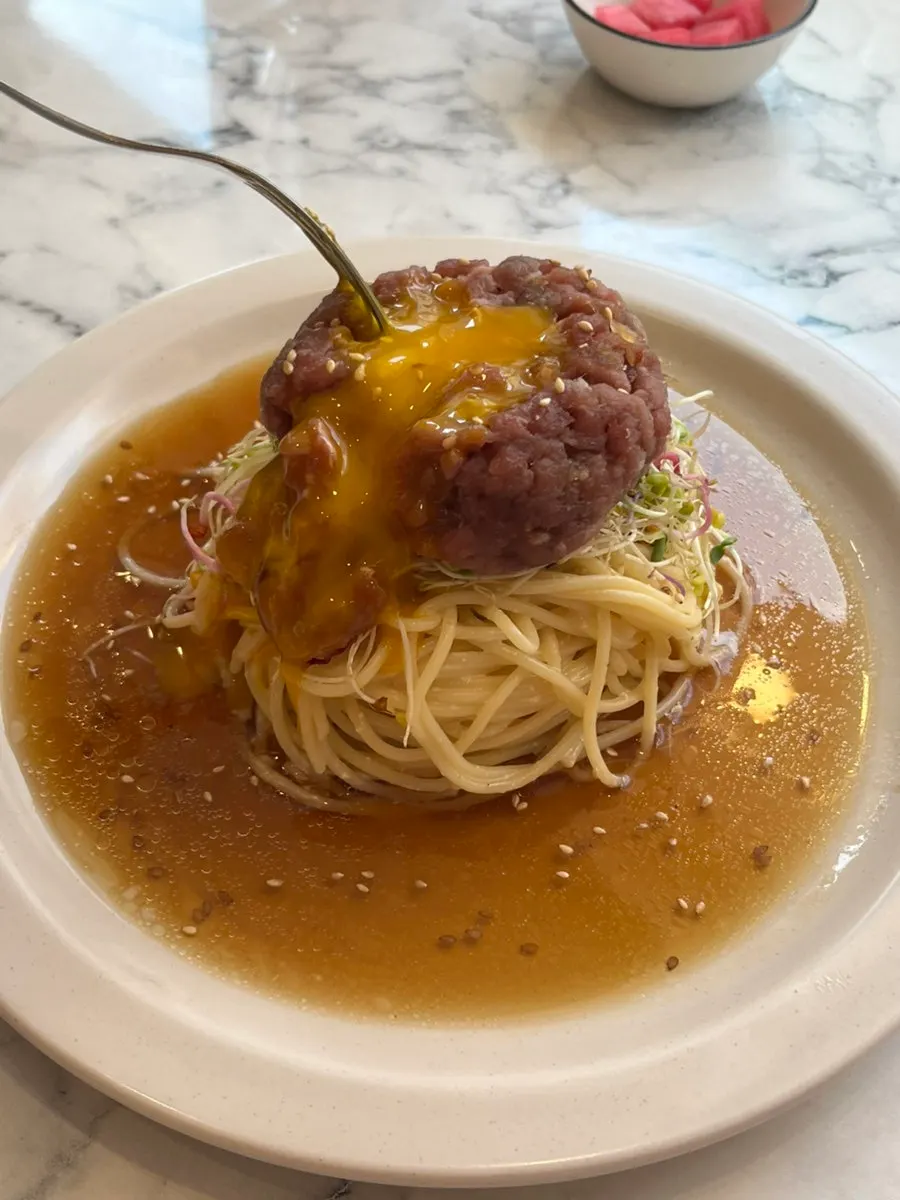 Egg yolk placed on top of the perilla oil beef tartare pasta