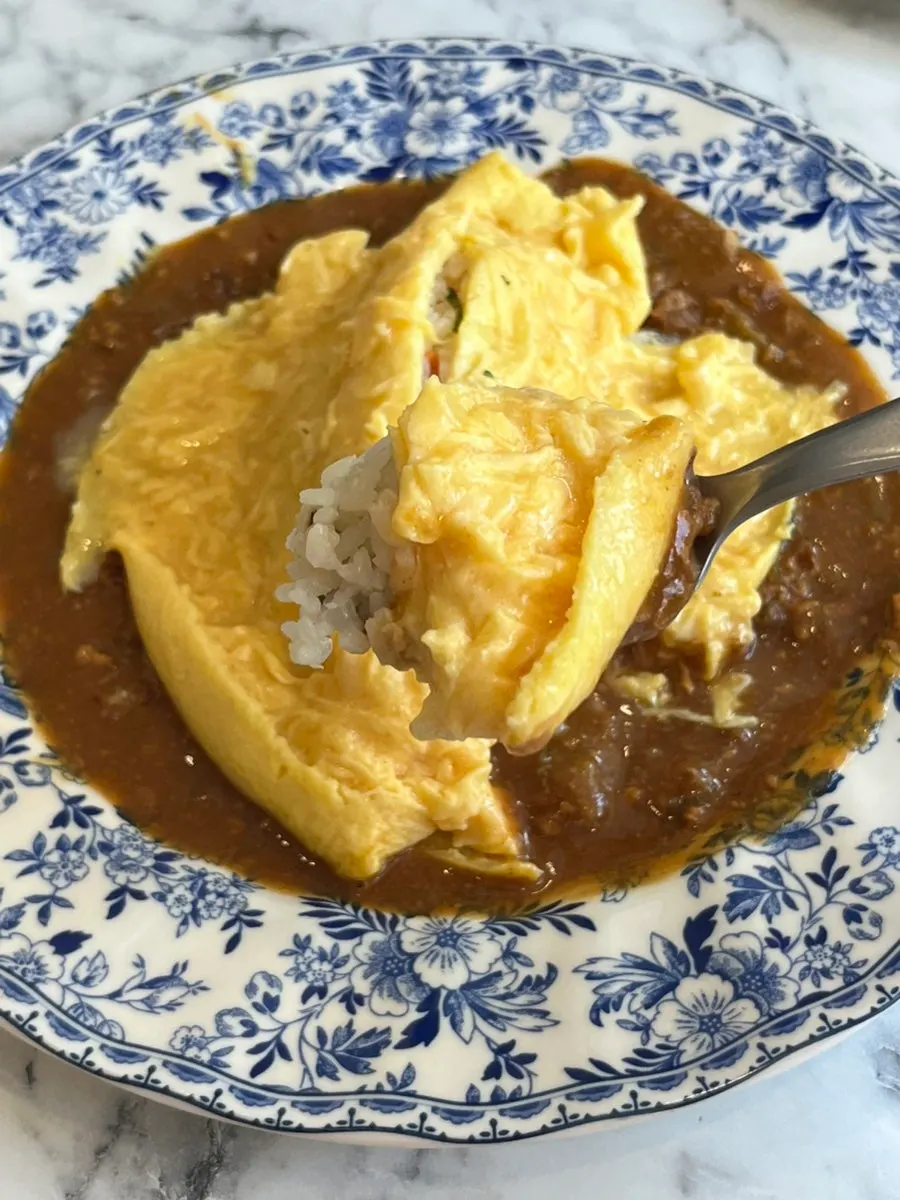 Omurice topped with curry sauce and creamy sauce