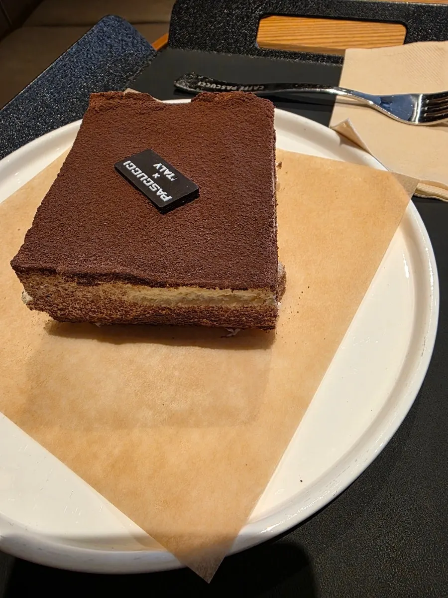 Table with an iced americano and two slices of cake