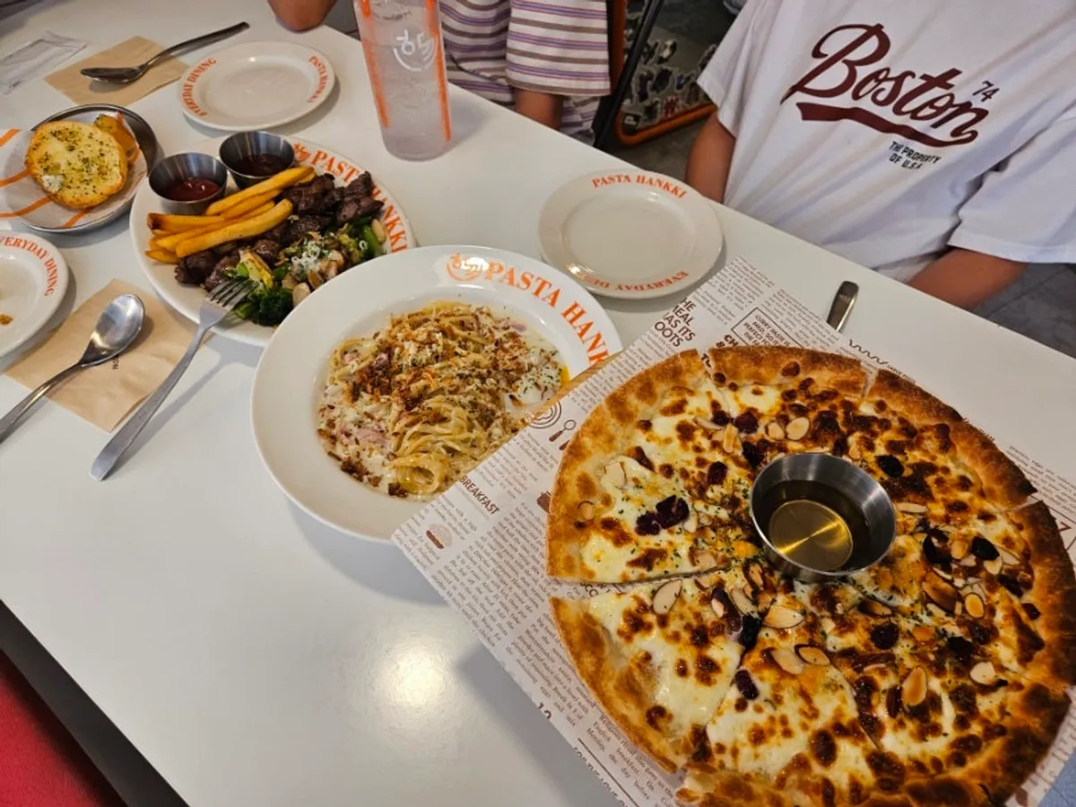 A full spread of pasta, pizza, and steak on the table