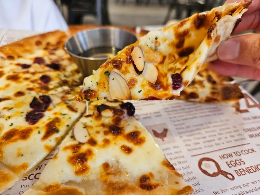 A slice of gorgonzola pizza drizzled with honey