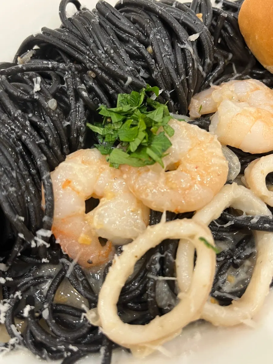 Close-up of black squid-ink pasta topped with herbs