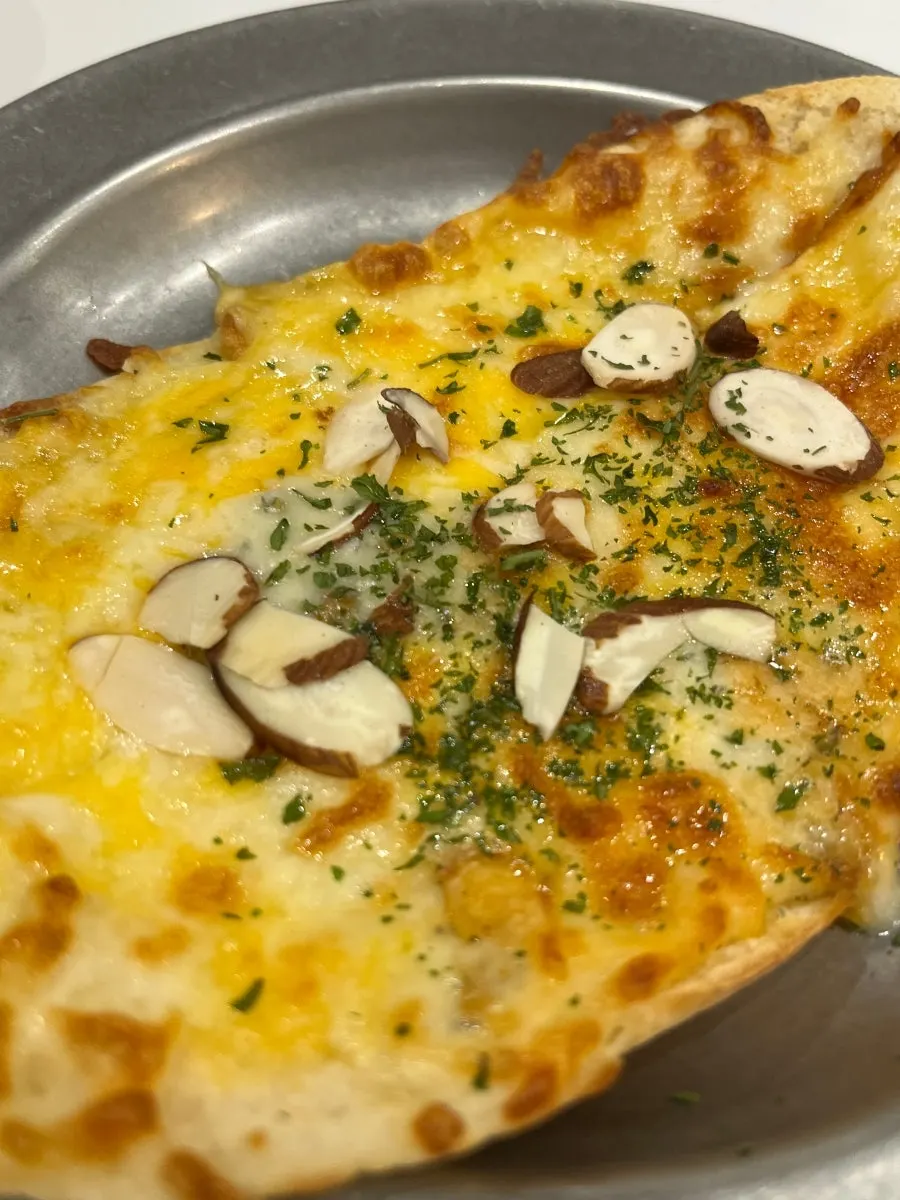 Gorgonzola mini pizza topped with sliced almonds and herbs
