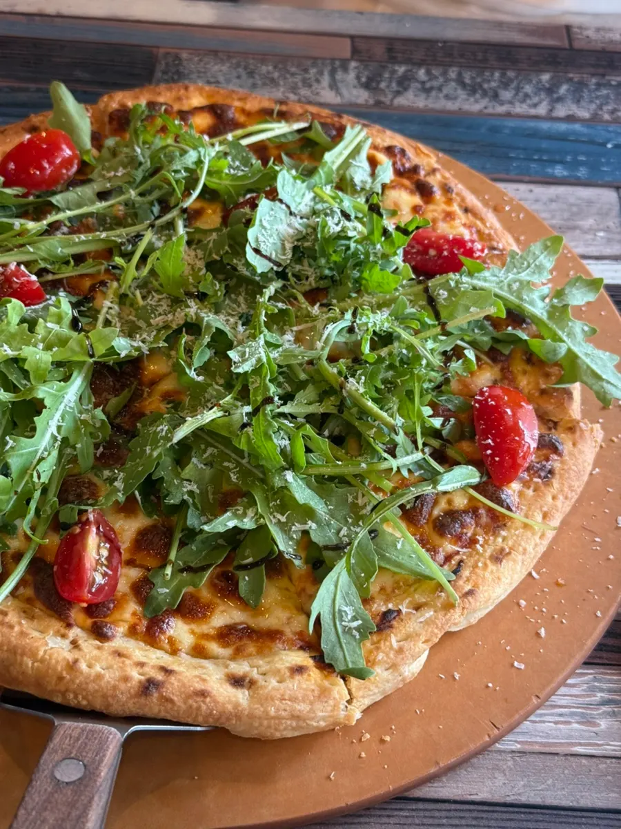 Large-size rucola pizza served at the table