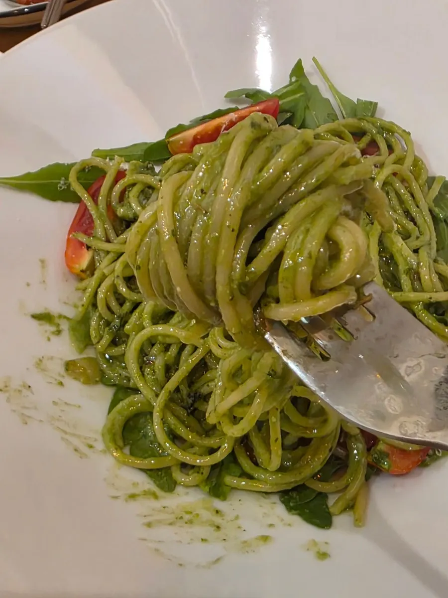 Basil pesto pasta topped with arugula and tomato