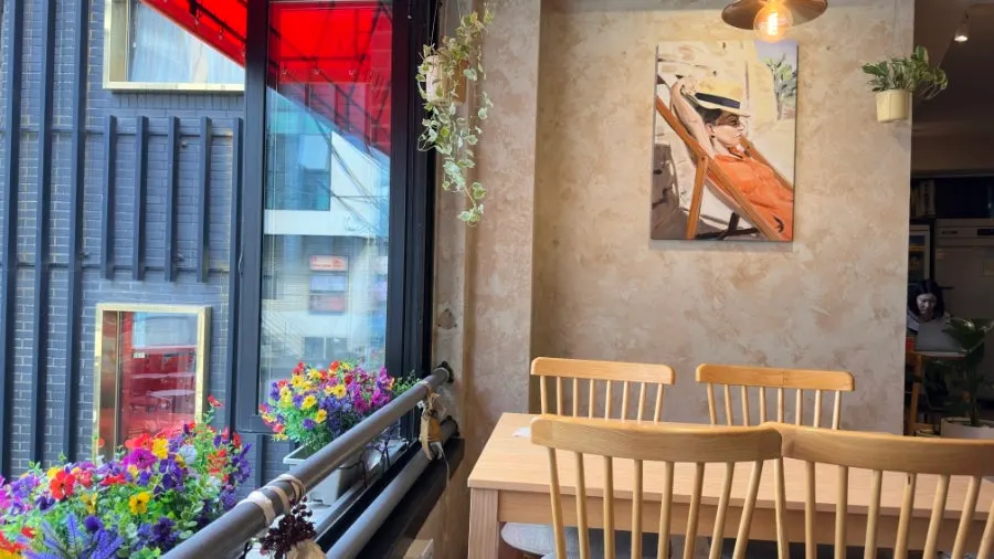 Window seat at Pastiar overlooking a flower garden through floor-to-ceiling glass