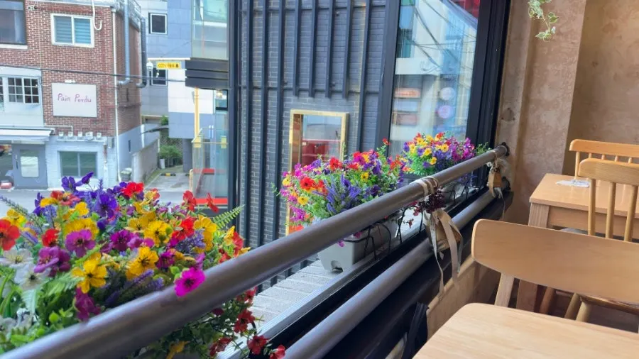 Second-floor window seat with an open window and flower garden view