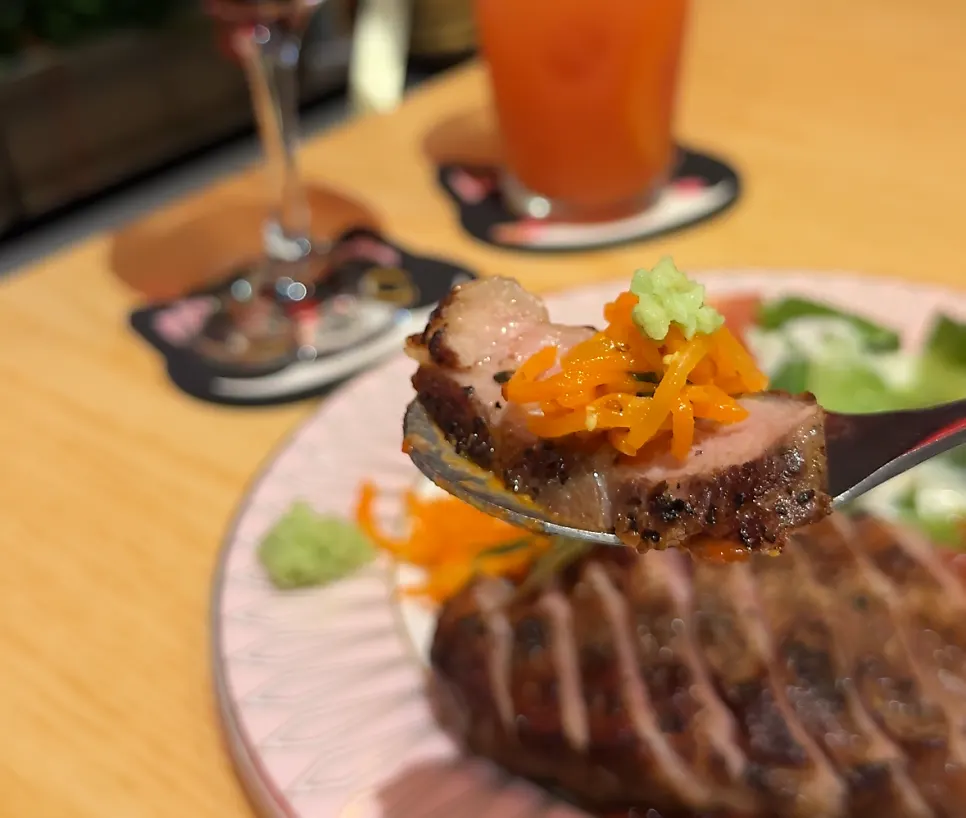 A bite of steak topped with carrot slaw and wasabi