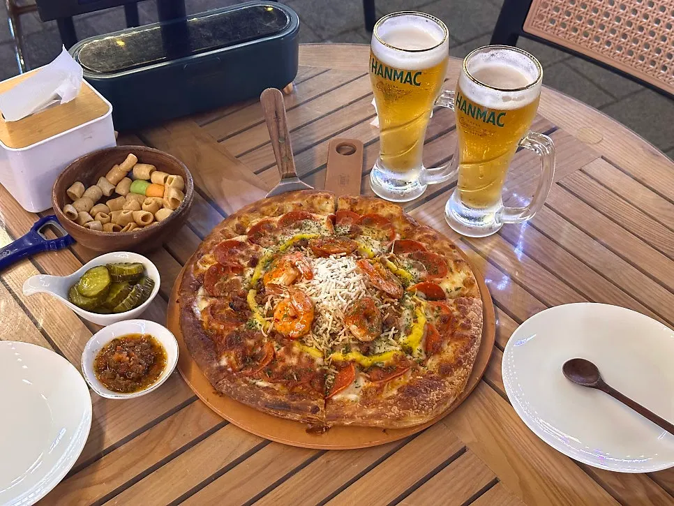 야외 테이블에 차려진 피자와 생맥주 상차림