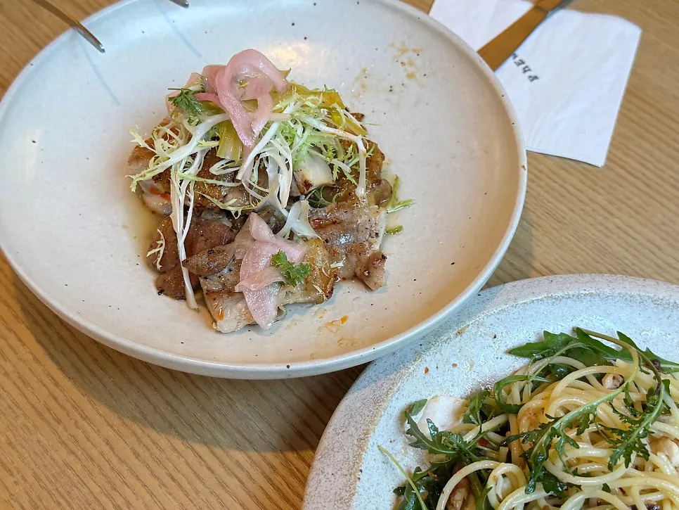 Table set with pasta, grilled chicken thigh, and juices together