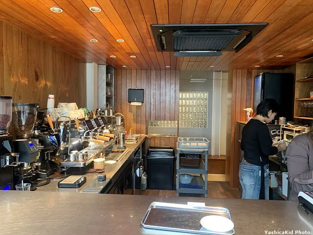 Kitchen behind the counter lined with grinders and espresso machines