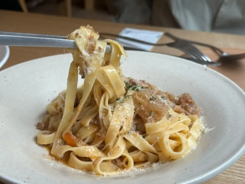 Lifting a forkful of ragu pasta